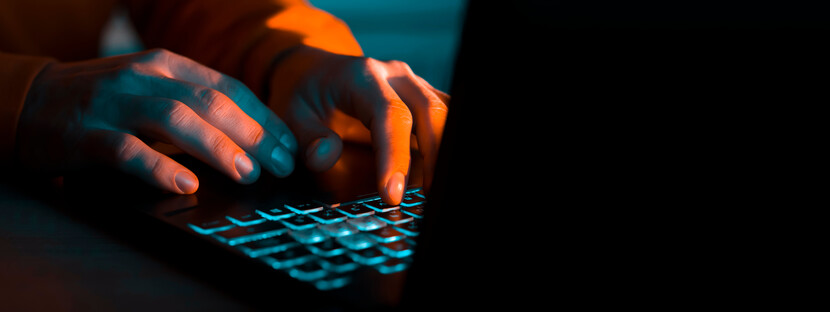 hands in blue and orange lighting using laptop