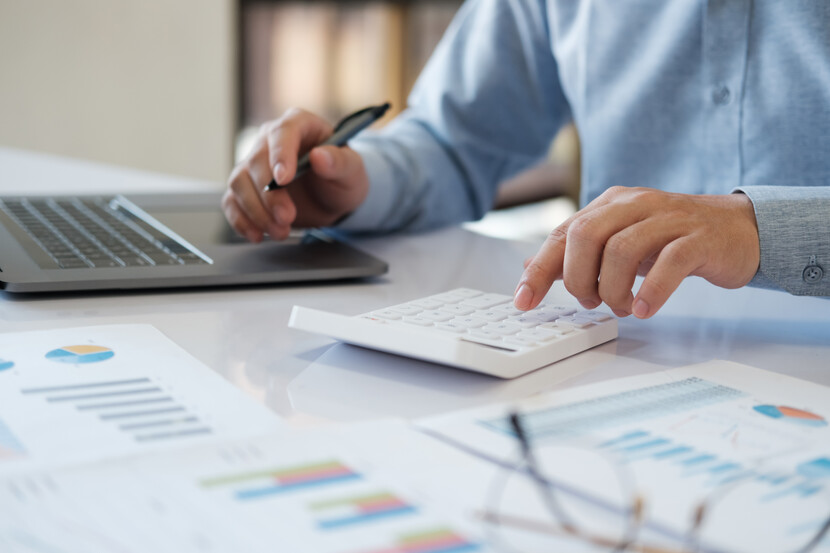 person on laptop with calculator and papers